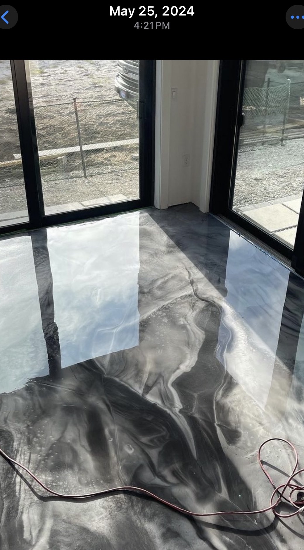 Silver and charcoal metallic epoxy floor with reflective finish near large windows